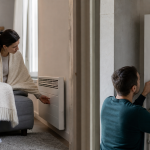 Femme ajustant un radiateur mural, enfant jouant à côté